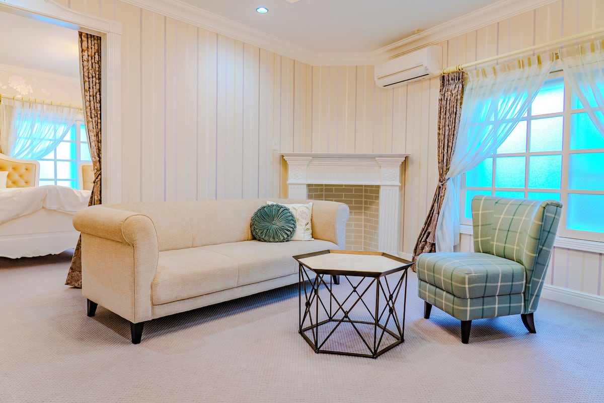 A room with a beige sofa, a green plaid armchair, and a geometric coffee table.