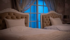 Un dormitorio con dos camas, cada una con cabecero acolchado y ropa de cama blanca.