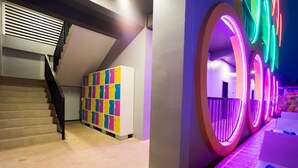 A modern interior with a staircase, colorful lockers, and illuminated circular structures. - White Rabbit Hostel - Adults Only (Siem Reap)