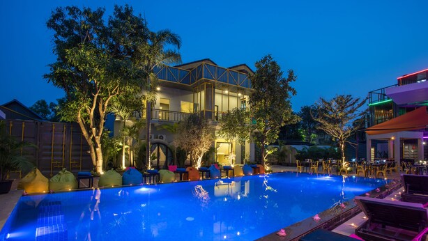 A swimming pool with lounge chairs and a building with multiple balconies. - White Rabbit Hostel - Adults Only (Siem Reap)