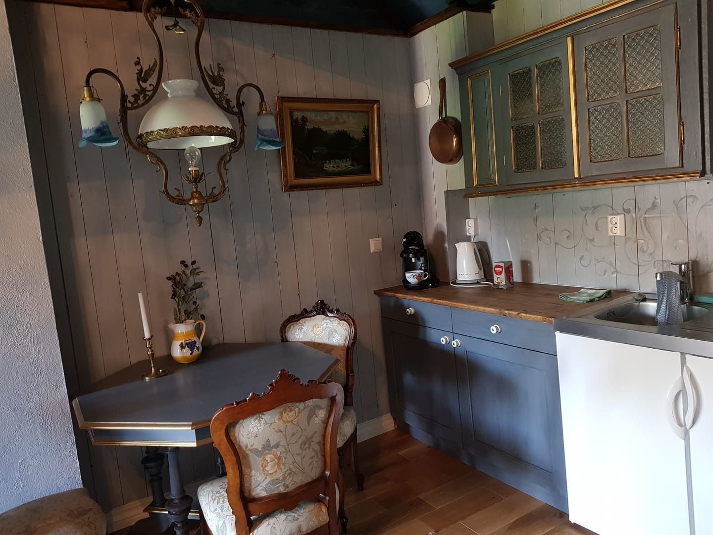 A kitchen with a wooden table, a chair, a sink, and a stove.