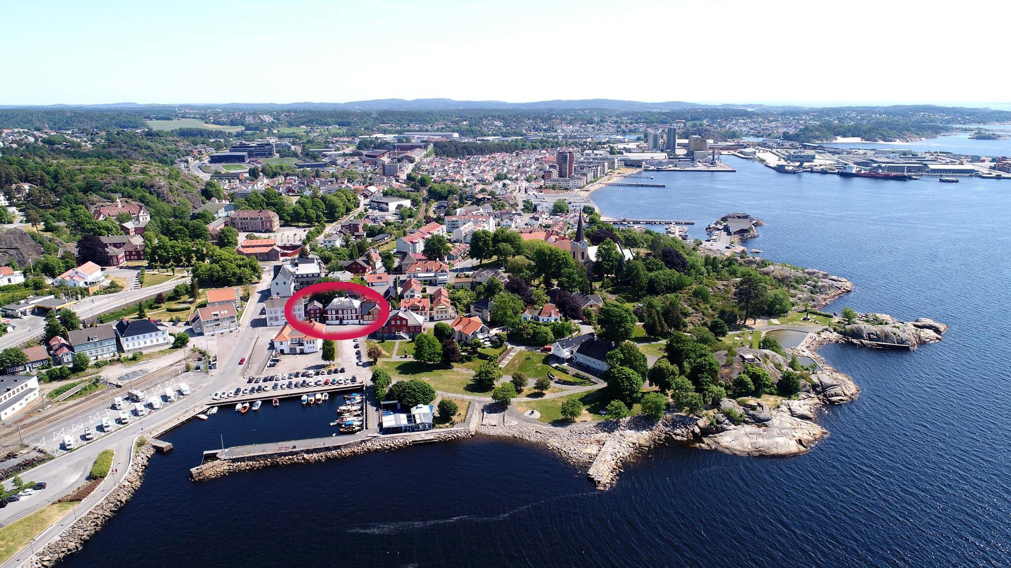 Vue aérienne d’une ville côtière avec un port de plaisance, des zones résidentielles et une église imposante.