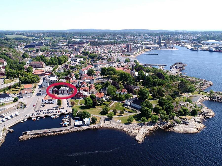 Vue aérienne d’une ville côtière avec un port de plaisance, des zones résidentielles et une église imposante.