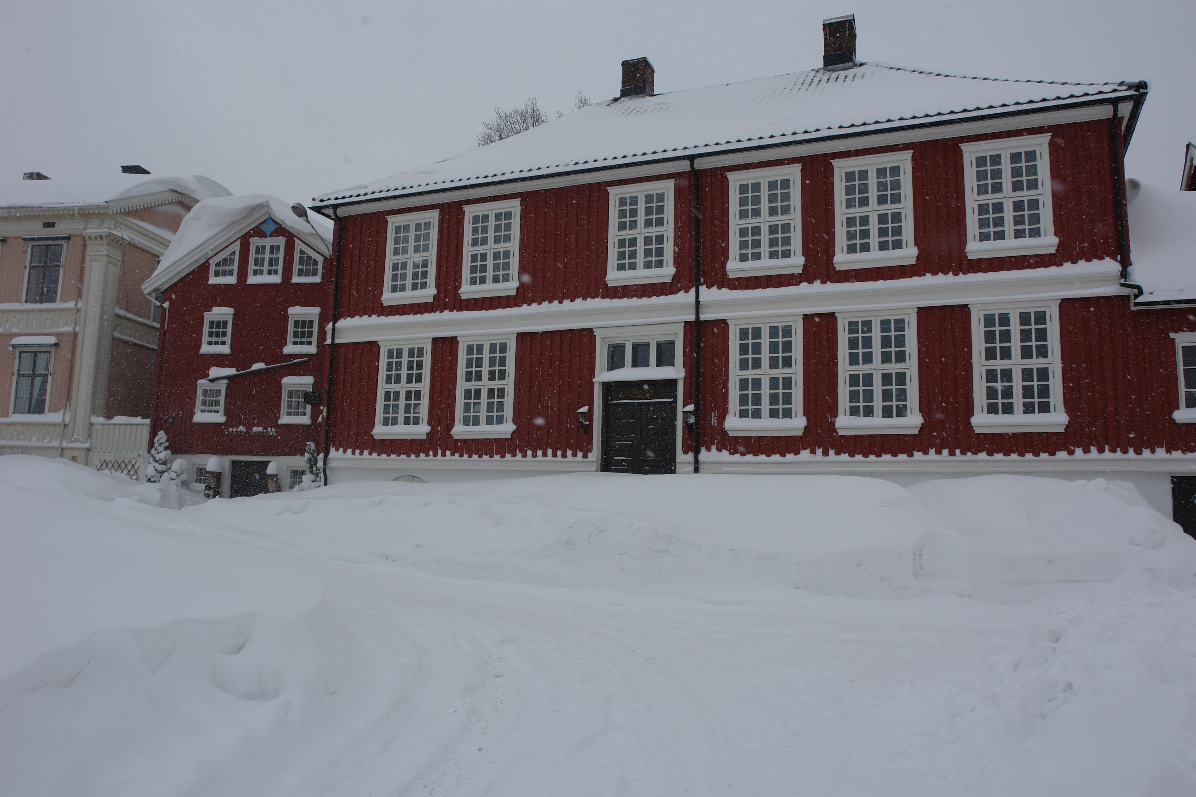 A red two-story building with white trim and multiple windows.