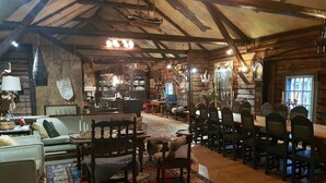 Interior rústico de una cabaña de troncos con comedor, muebles de madera y una alfombra grande.