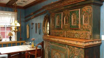 A room with a wooden dining table, chairs, a chandelier, and a decorative cabinet with intricate designs.