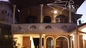 A two-story house with a covered patio area, a bicycle, and a chair. - Villa De Rosh (Negombo)