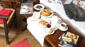 Una sala de estar acogedora con chimenea, un sofá con cojines estampados, una mesa de comedor con alimentos para el desayuno y una estantería.