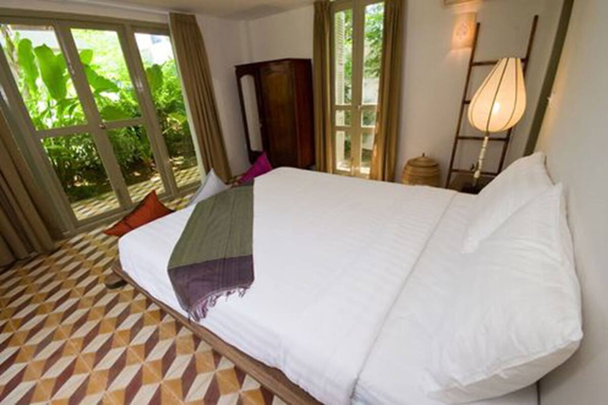 Un dormitorio con una cama, una ventana y una lámpara.