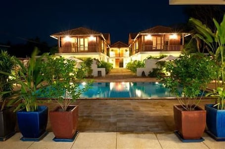 Una piscina al aire libre, sombrillas, sillones reclinables de piscina