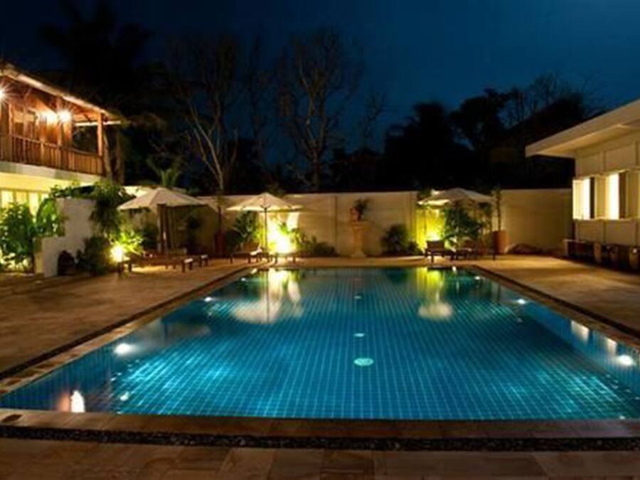 Una piscina con bordo piastrellato, circondata da zone relax e ombrelloni.