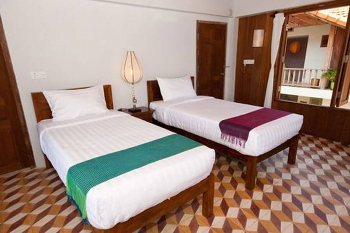 Habitación de hotel con dos camas, piso estampado y puerta de madera.