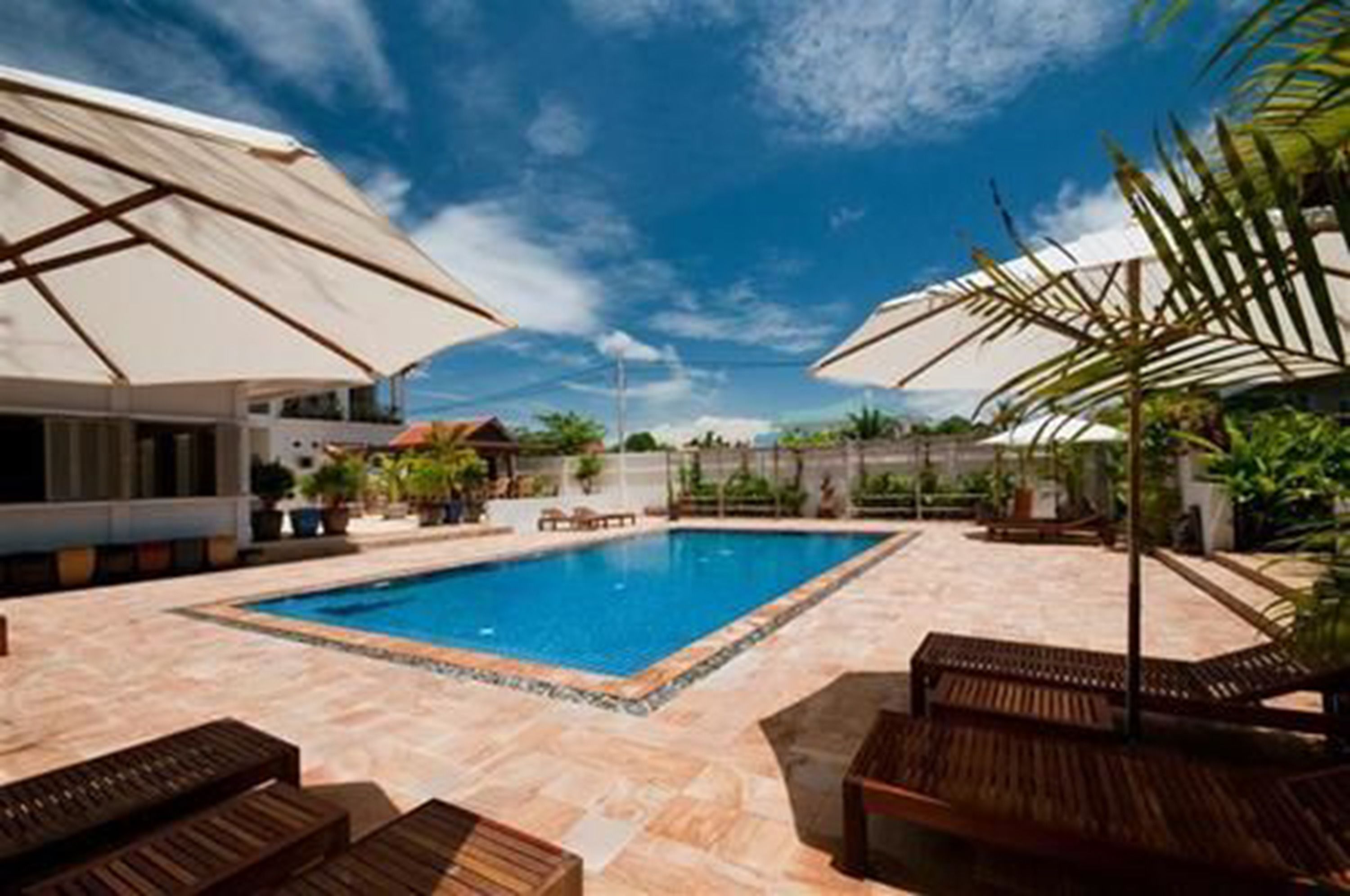 A swimming pool with lounge chairs and umbrellas, surrounded by a tiled patio.