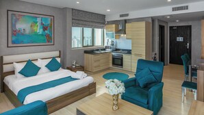 Habitación de hotel moderna con cama, zona de estar, kitchenette y vista a la ciudad.