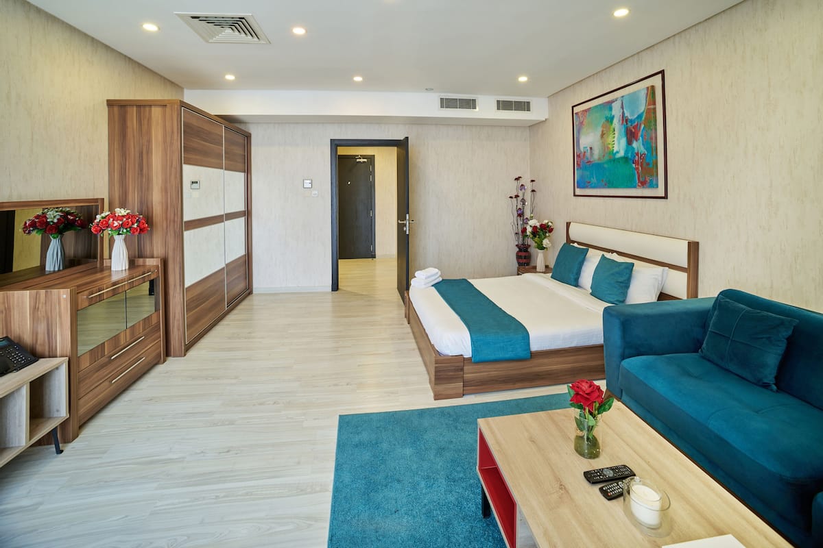 A modern hotel room with a bed, a sofa, a desk, and a cabinet.