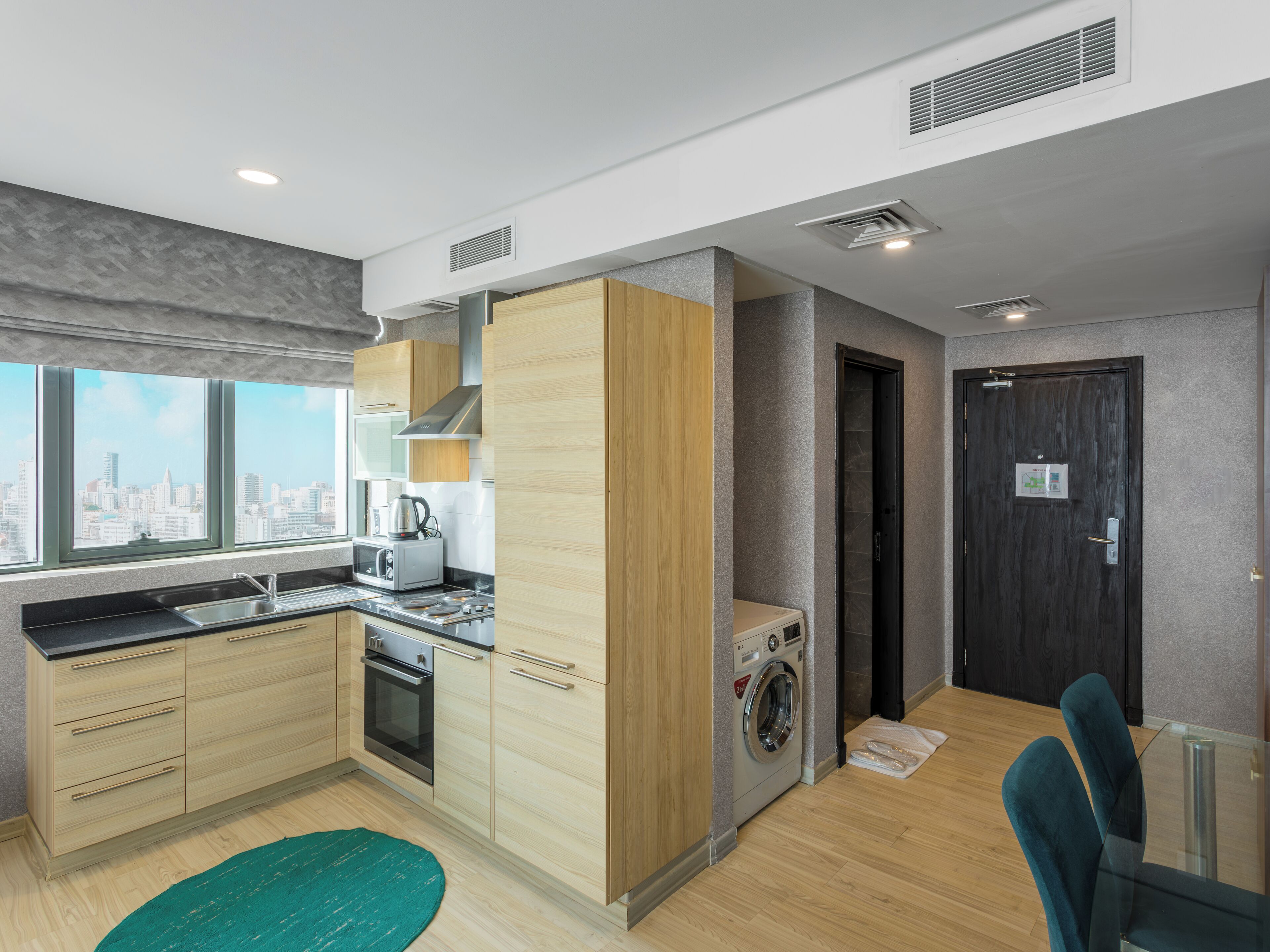 Una cocina moderna con horno empotrado, microondas y tostadora, lavadora y un amplio ventanal con vistas a la ciudad.