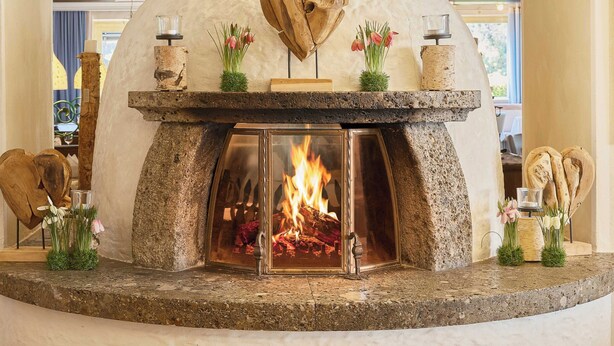 A stone fireplace with a heart-shaped design, a fire burning inside, and decorative items on the mantel.