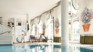 A swimming pool with a clear reflection, sunlit interior, and a view of the outside.