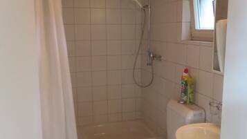 A small bathroom with a shower, toilet, and sink.