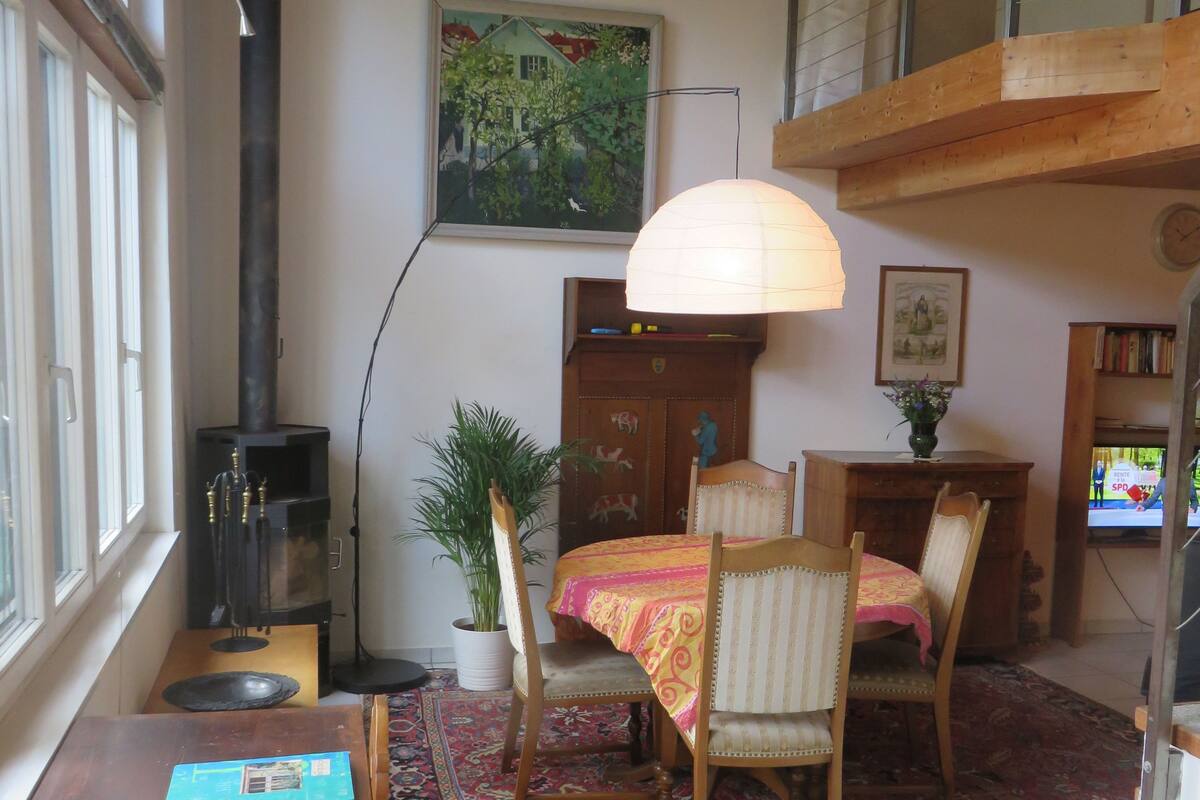 Una sala de estar acogedora con chimenea, muebles de madera, una mesa de comedor y un ventanal grande.