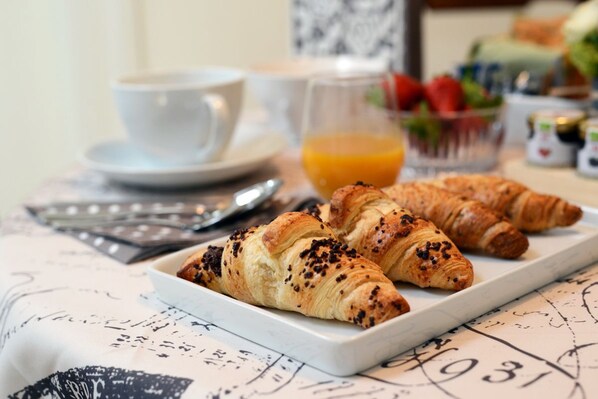 A breakfast setting with croissants on a plate, a cup, and a glass of orange juice.