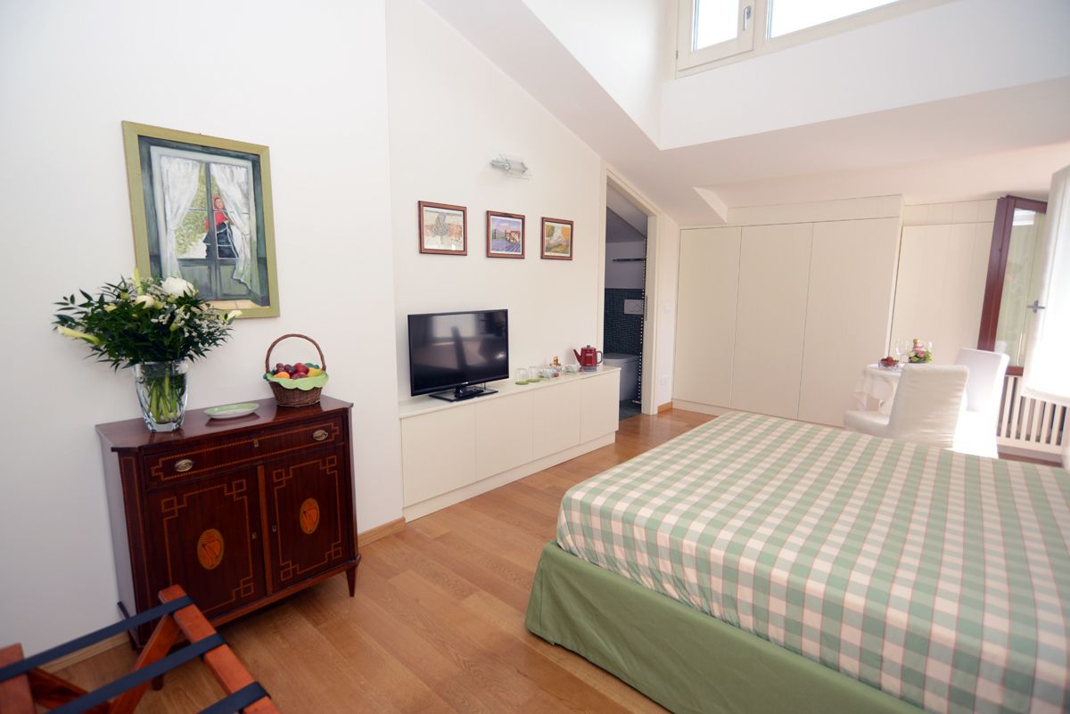 A bedroom with a bed, a TV, a dresser, and a window with curtains.