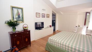 A bedroom with a bed, a TV, a dresser, and a window with curtains.