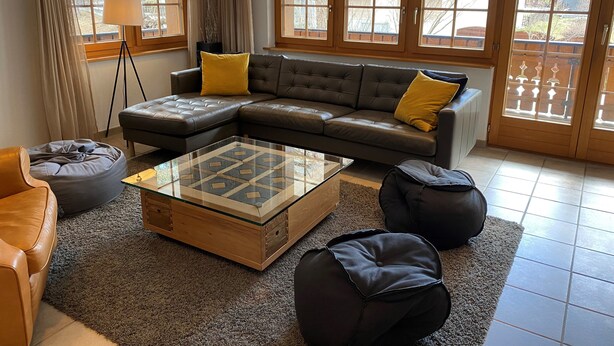 A modern living room with a sectional sofa, a glass coffee table, and a cozy rug. - Haus Ares (Zermatt)