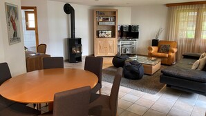 A living room with a fireplace, a dining table, and a sofa. - Haus Ares (Zermatt)