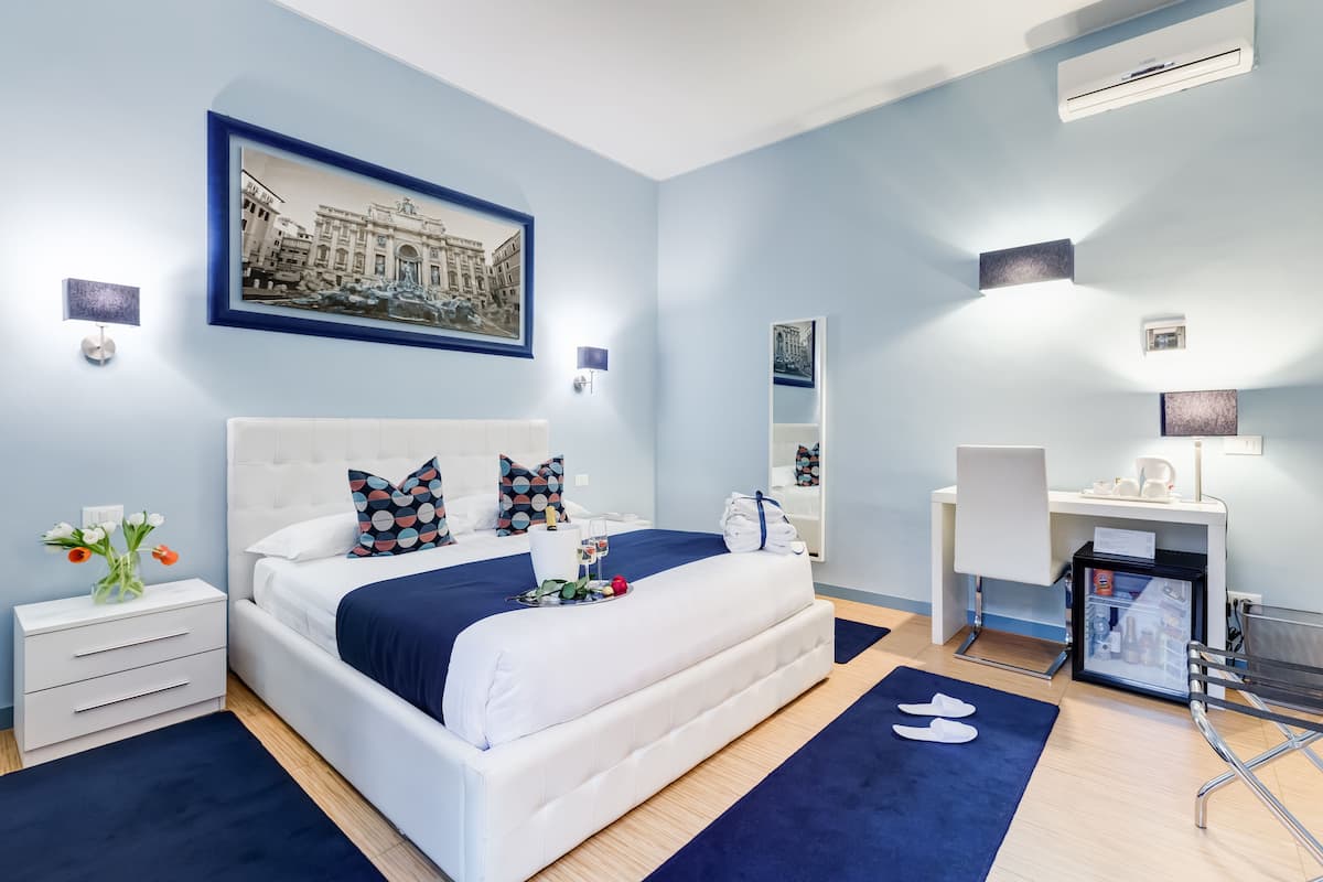 Una habitación de hotel moderna con una cama grande, un escritorio y un refrigerador.