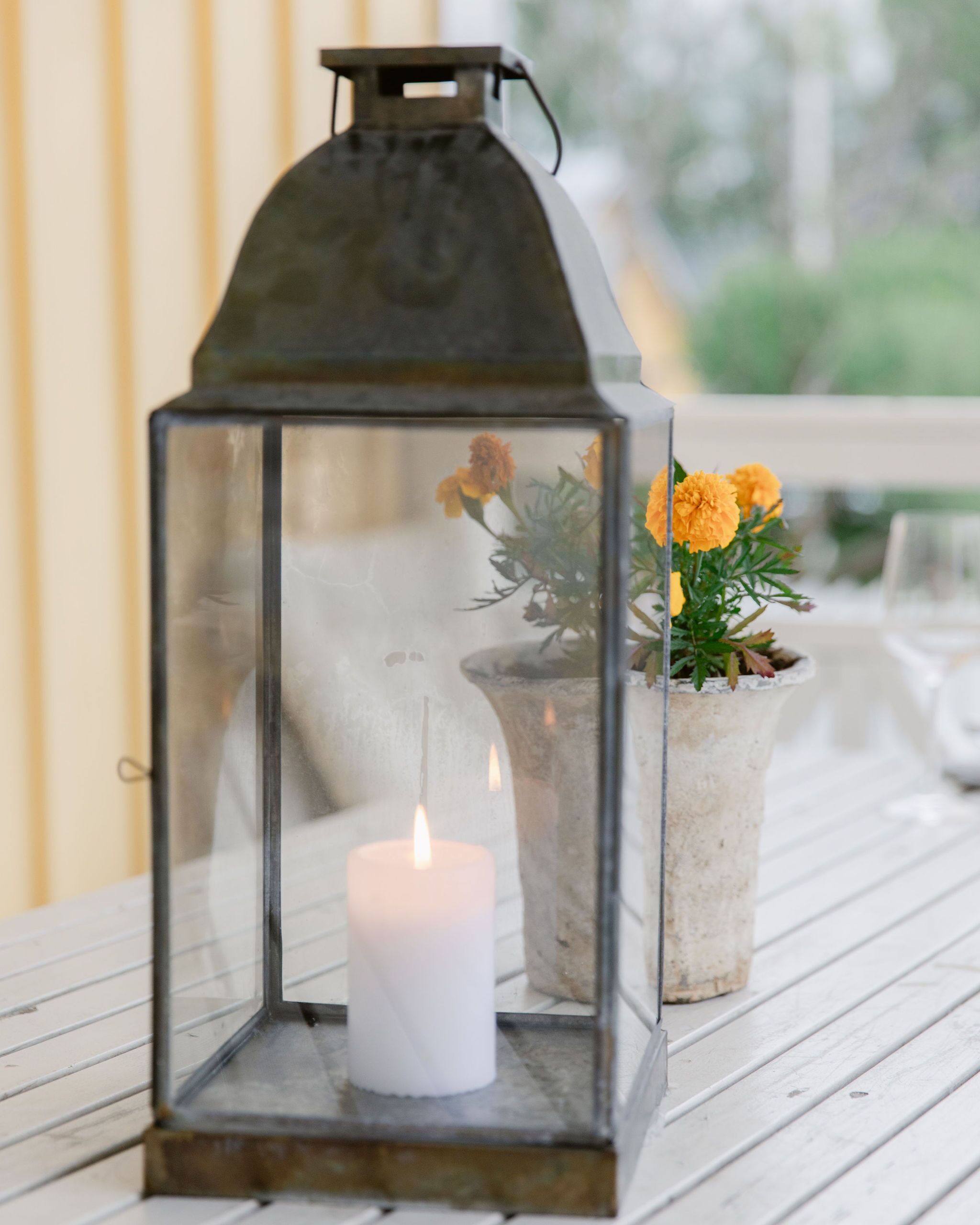Um candeeiro com uma vela no interior, sobre uma superfície de madeira.