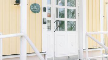 A building with a white door and yellow walls, a sign reading "Lillan Hotel," and a metal railing in front.