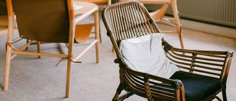 Une pièce avec des chaises en osier, une table et de grandes fenêtres.