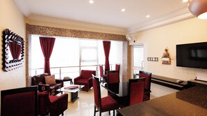 A hotel lobby with a seating area, a flat-screen TV, and a large window with curtains. - The Ritzz Exclusive Guest House (Accra)