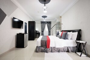 A modern bedroom with a bed, TV, and a staircase. - The Ritzz Exclusive Guest House (Accra)