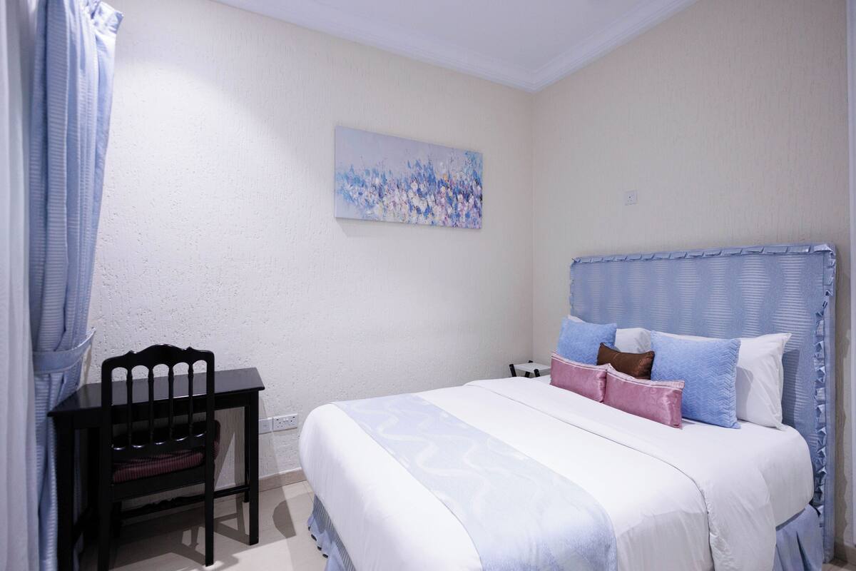 Ein Schlafzimmer mit einem Bett, einem Sessel, einem Bild an der Wand und einem Nachttisch.