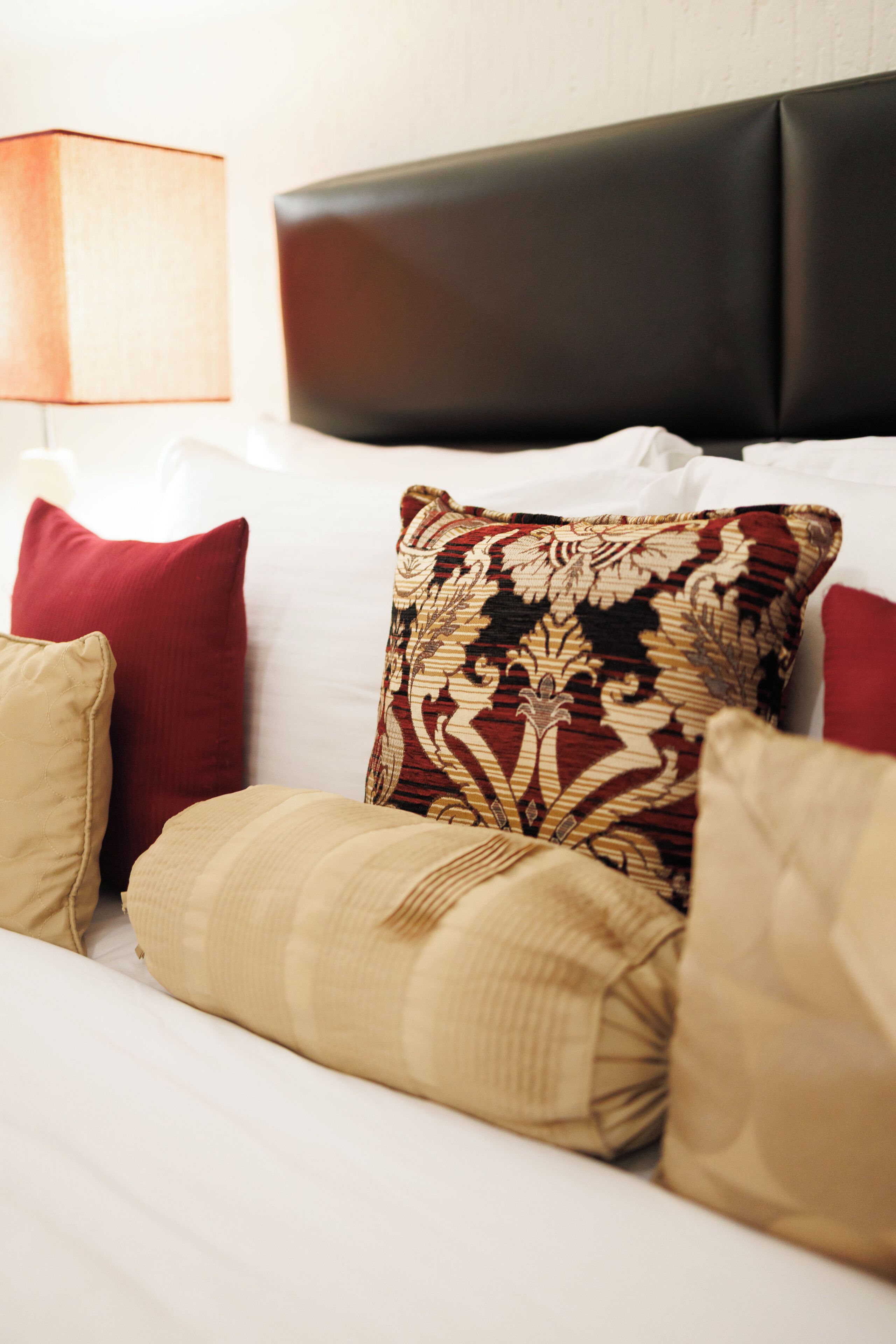 A bed with a headboard, multiple pillows, and a bedside lamp.