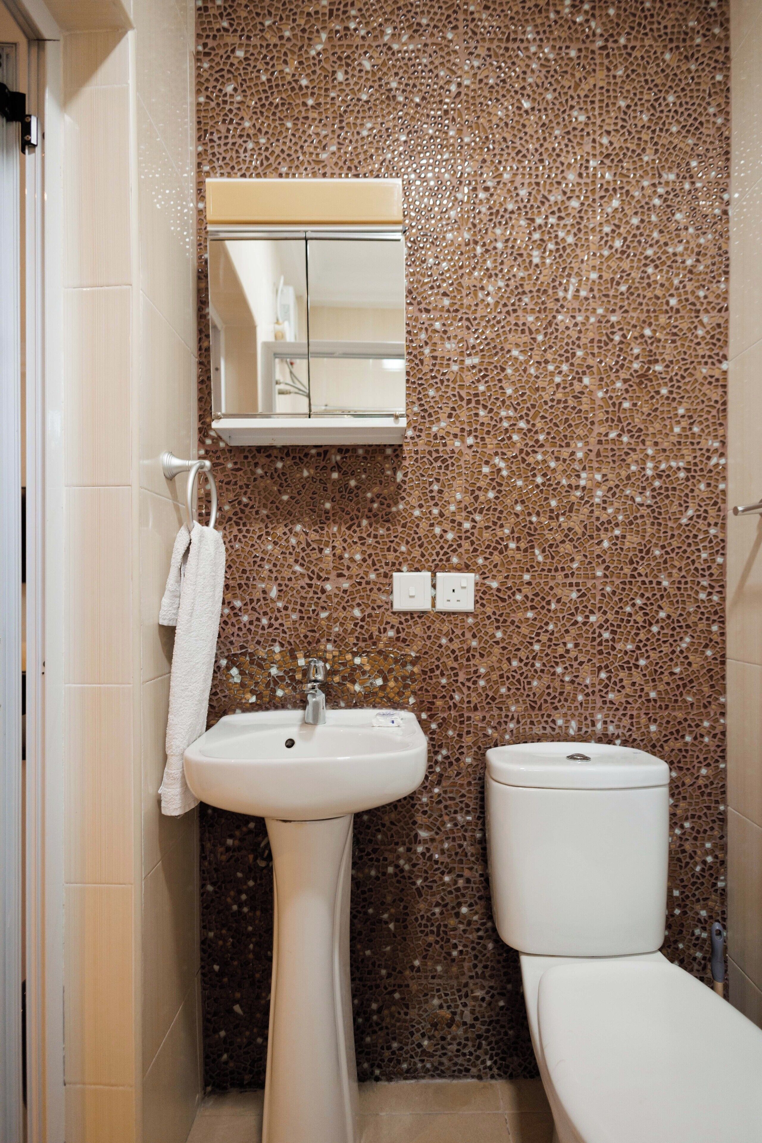 Une salle de bain avec un mur recouvert de mosaïques, un lavabo et des toilettes.