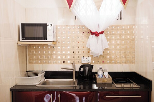A kitchen with a microwave, sink, and stove. - The Ritzz Exclusive Guest House (Accra)