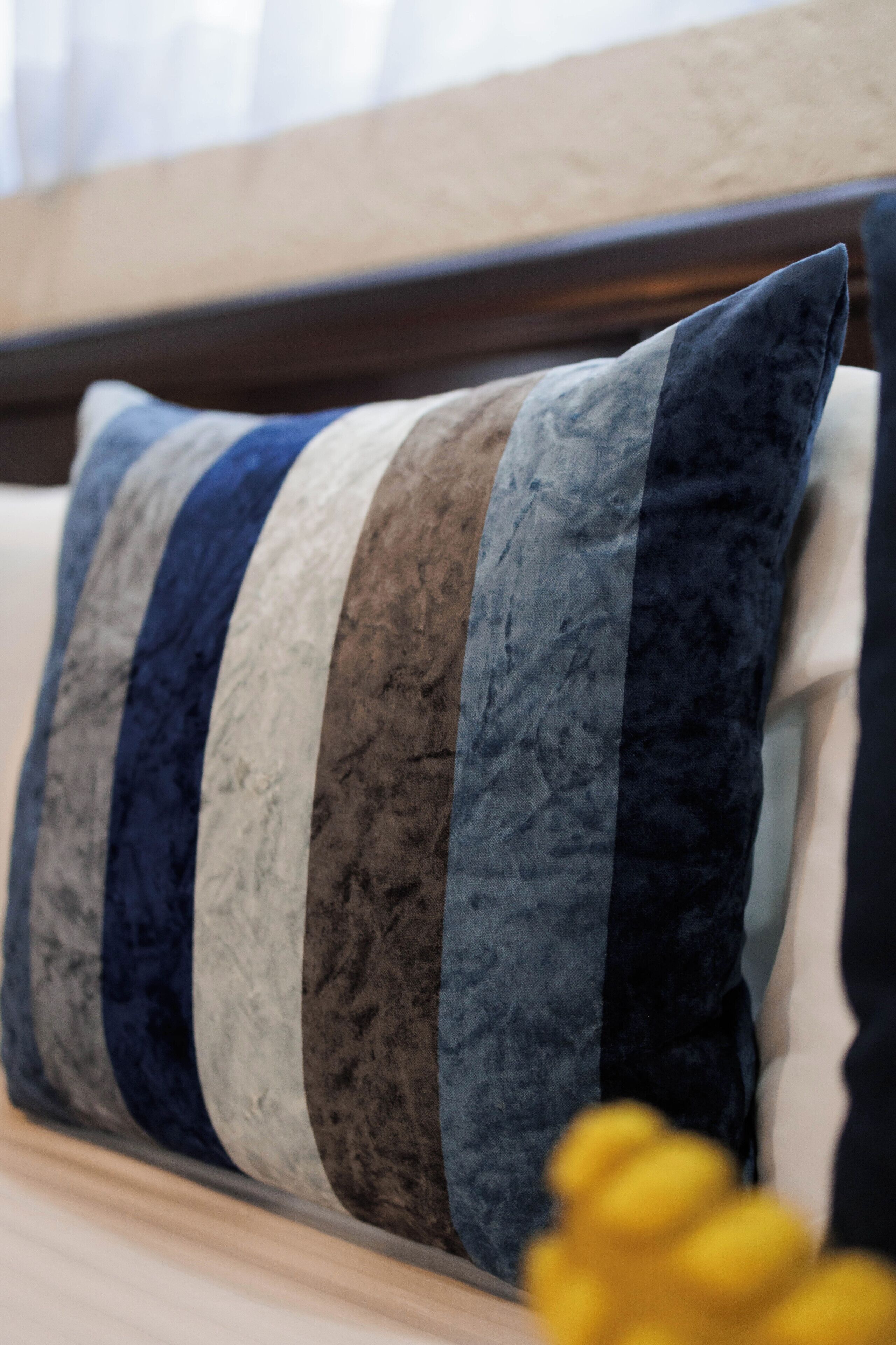 A bed with a headboard and a pillow with a striped pattern.