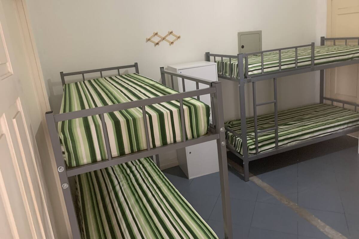 Ein Schlafsaalzimmer mit Etagenbetten, einem Schreibtisch und einem kleinen Schrank.
