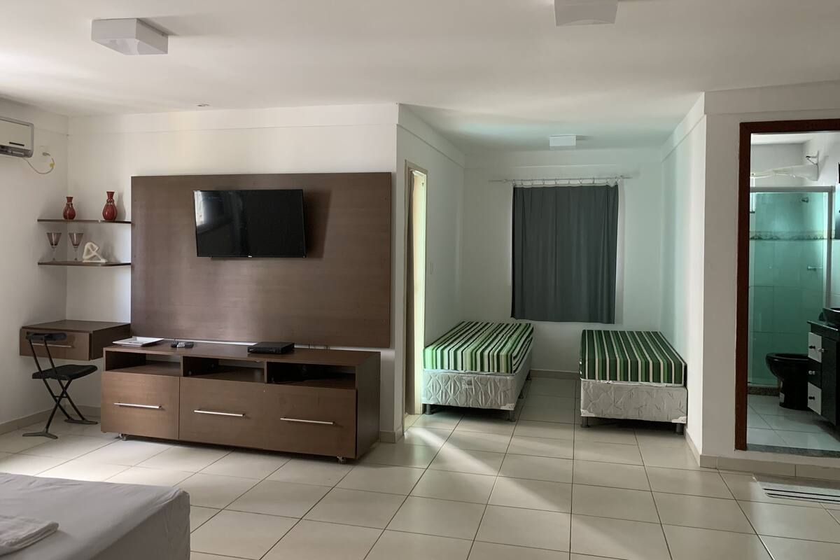 Ein Schlafzimmer mit einem Bett, einem Fernseher, einem Schreibtisch und zwei Nachttischen.