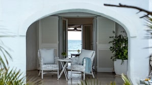 A white-walled room with a view of the sea, featuring two wicker chairs and a small table. - La Peschiera (Monopoli)