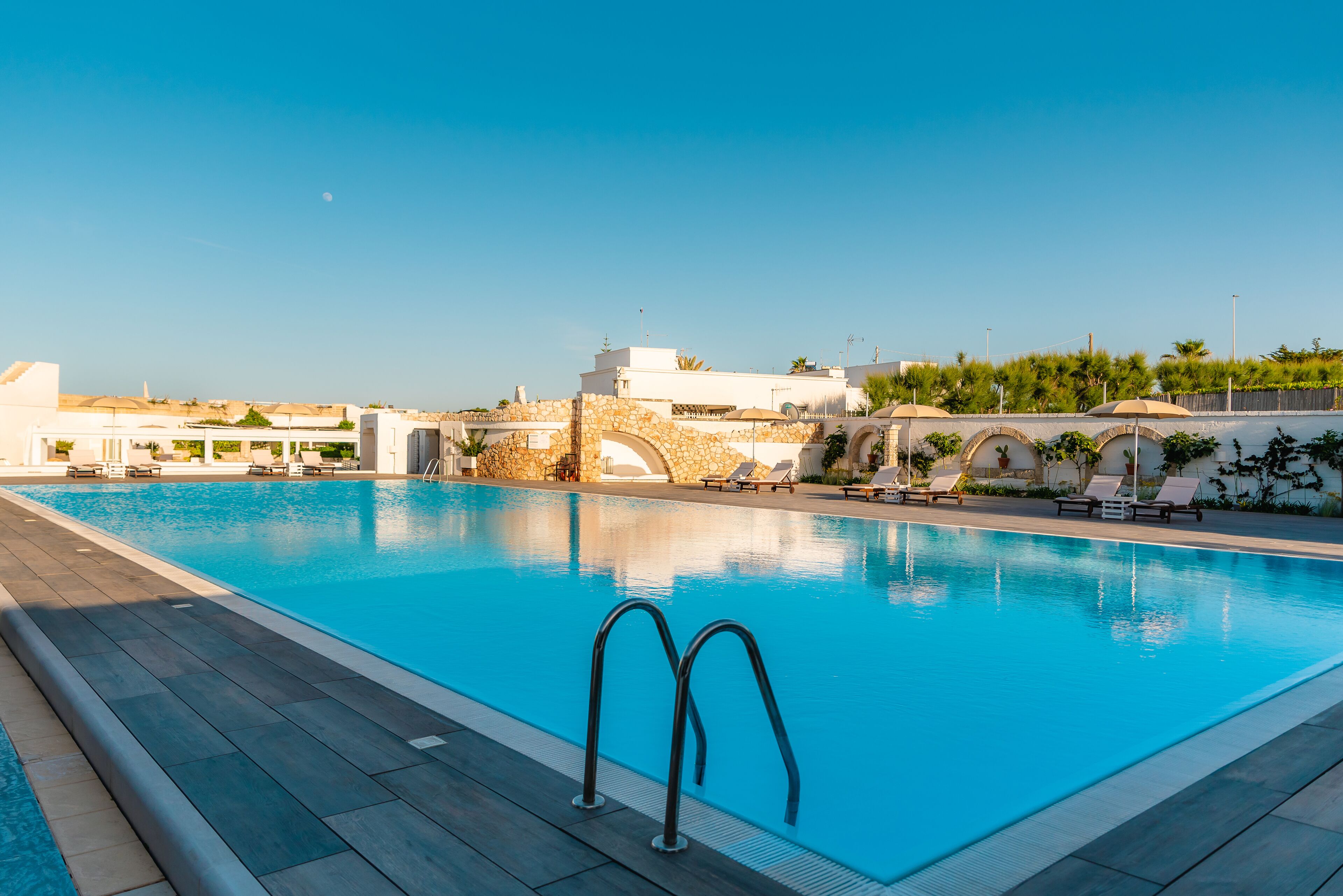 A swimming pool with lounge chairs and a stone bridge.