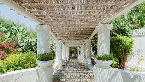 A covered walkway with white columns and potted plants. - La Peschiera (Monopoli)