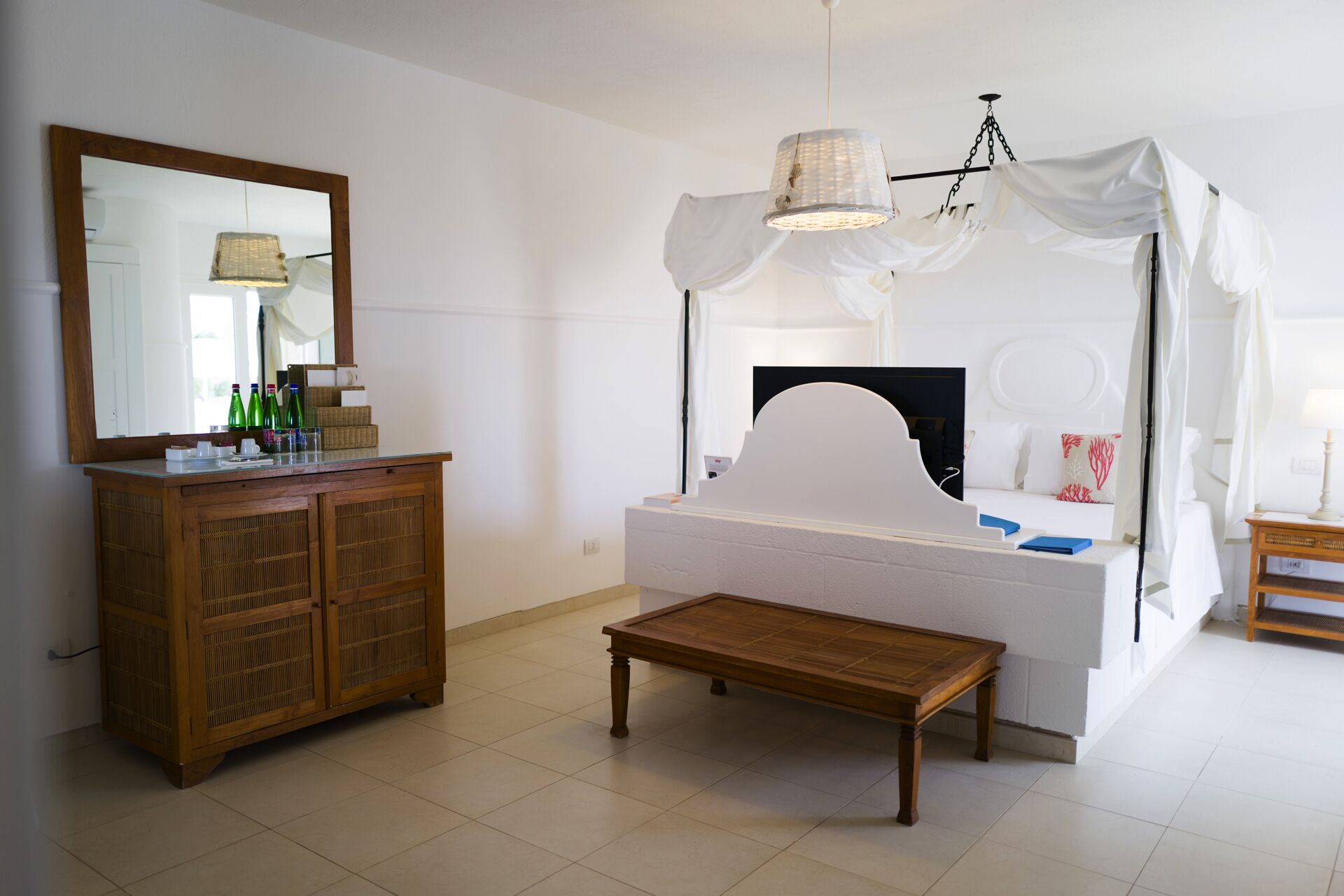 Una camera da letto con un letto a baldacchino, una cassettiera in legno, un comodino e uno specchio.