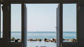 A view through a doorway to a coastal area with rocks and calm water. - La Peschiera (Monopoli)