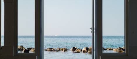 A view through a doorway to a coastal area with rocks and calm water.
