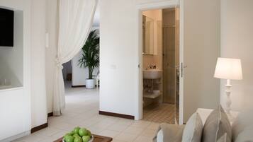 Una sala de estar moderna con una televisión, un tazón de manzanas verdes sobre una mesa de madera y un sofá con almohadones.
