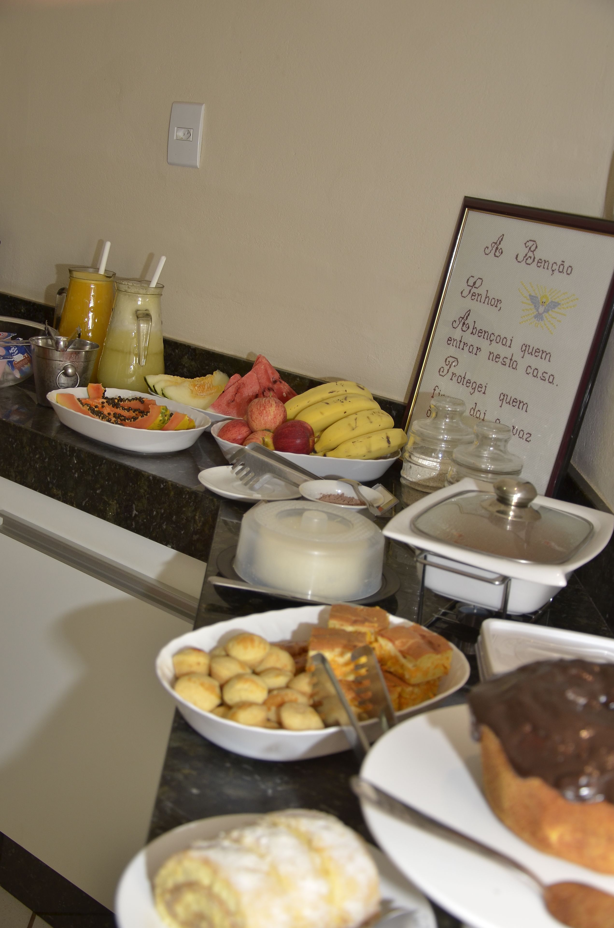 A buffet with various food items including fruits, pastries, and a sign with a message.